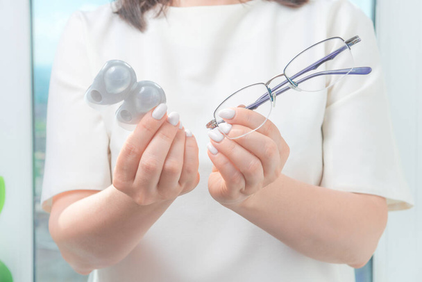 the woman holds glasses in one hand and one-day contact lenses in the other. myopia and eyesight, problem with vision concept - Photo, Image