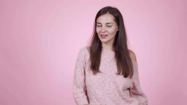 Woman in pink knitted sweater posing on camera isolated on pink background - Filmmaterial, Video
