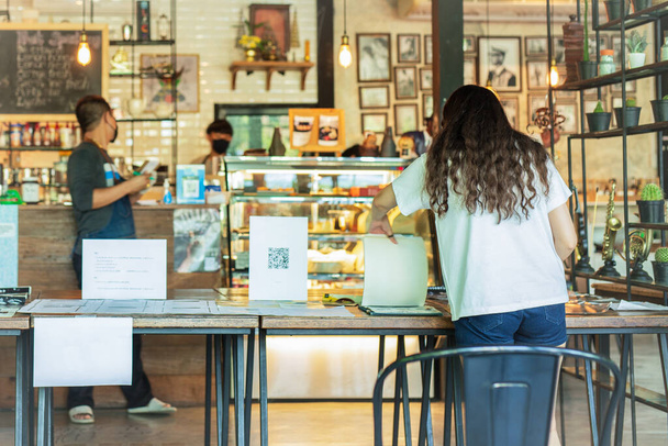 Κοινωνική απόσταση εννοιολογική γυναίκα πελάτης κοιτάζοντας μενού με σερβιτόρος στέκεται στο καφέ - Φωτογραφία, εικόνα