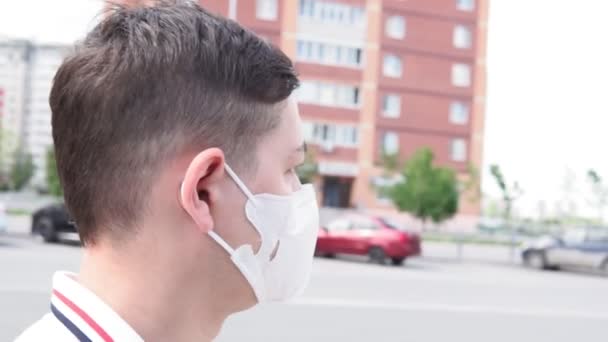 Sırt çantasıyla yürüyen ve kendini koronavirüsten korumak için yüz kirliliği maskesi takan bir adam.. - Video, Çekim