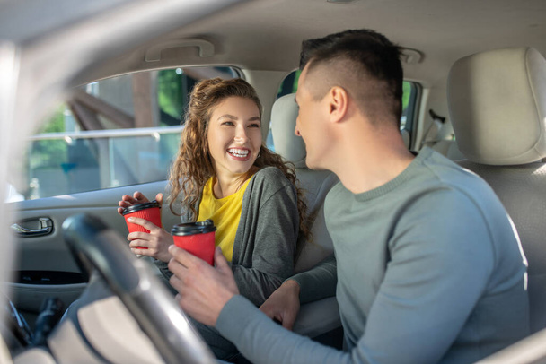Woman and man sitting in car with glasses of coffee. - Photo, Image