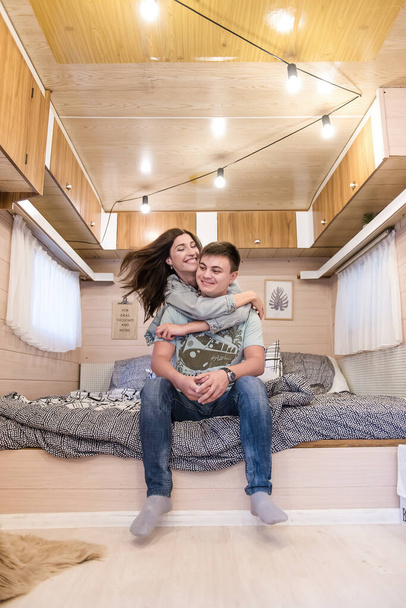 Beautiful brunette girl hugs a young man, a couple in love kisses, looks at each other, kiss. Lovers have fun while traveling in their motor home.  Concept Caravan and relaxing in the camping.  Travel - Fotografie, Obrázek