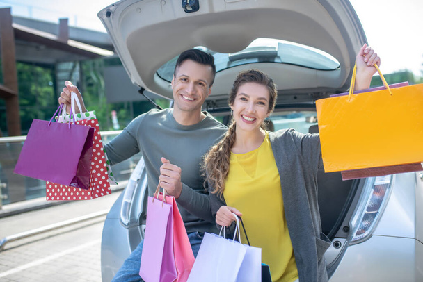 Young woman and man with many purchases near the car - Photo, Image