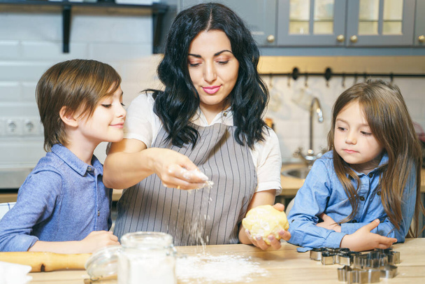 Happy family mom and two children cooking homemade cookies in the kitchen. - Photo, Image