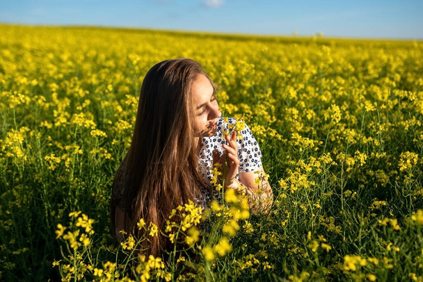 Una ragazza in un campo di colza, con i capelli sciolti, annusa la colza. Foto di alta qualità
 - Foto, immagini