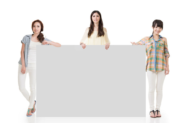 Three pretty women showing an empty board - 写真・画像