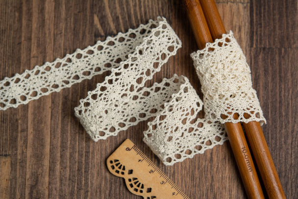 cintas de cinta de lino calado beige de punto en estilo rural de algodón rústico eco natural en suelo de madera
 - Foto, Imagen