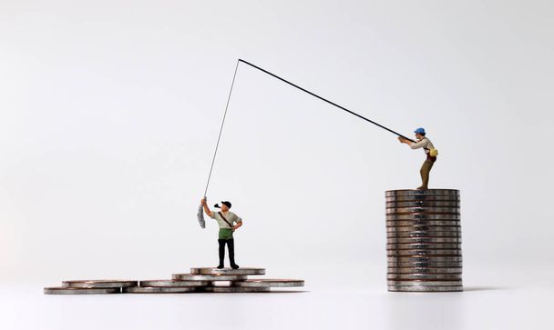 Le concept d'inégalité des revenus. Peuple miniature pêche et piles de pièces. - Photo, image