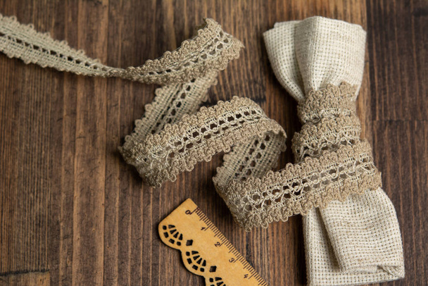 knitted beige openwork linen ribbon tapes in rural style of rustics cotton eco natural on wood ground - Zdjęcie, obraz
