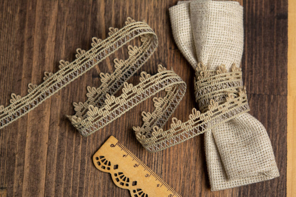 Gestrickte beige durchbrochene Leinenbänder im ländlichen Stil der rustikalen Baumwolle eco natural auf Holzboden - Foto, Bild
