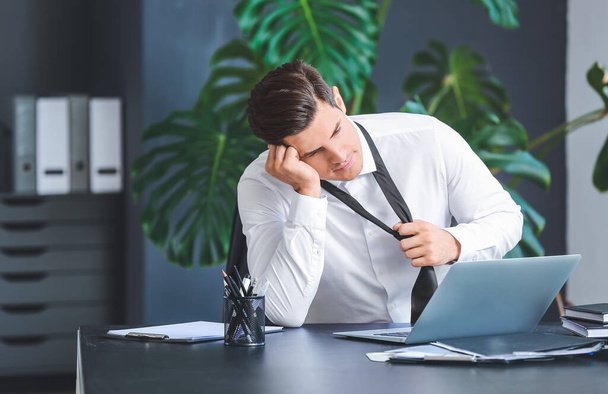Joven hombre de negocios cansado en la oficina soñando con fines de semana
 - Foto, imagen