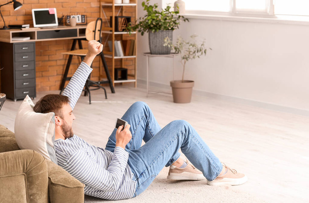 Hombre perezoso con teléfono móvil pasar el día libre en casa
 - Foto, Imagen