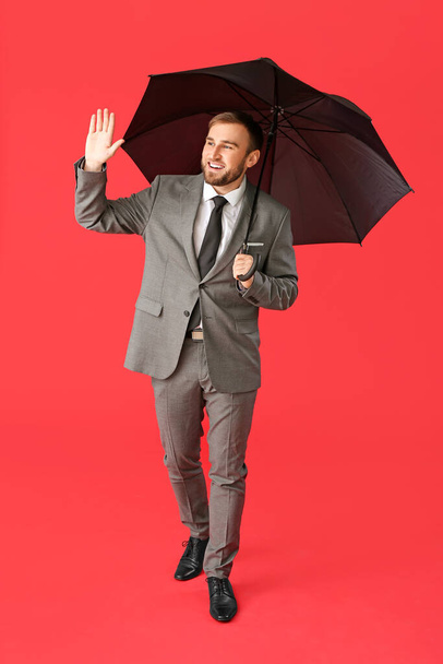 Hombre de negocios guapo con paraguas sobre fondo de color
 - Foto, Imagen