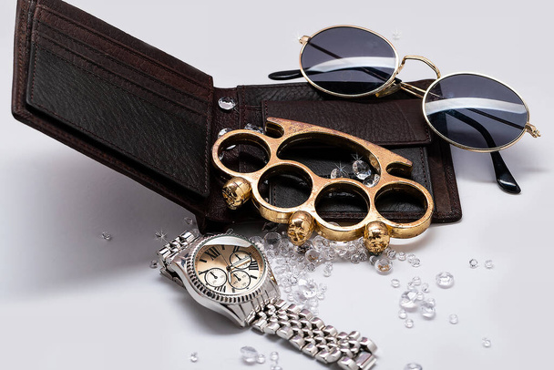 Punhos de bronze e relógio de ouro entre diamantes de cristal na carteira dos homens, close-up com foco seletivo.O conceito de roubo e máfia. luxo
 - Foto, Imagem