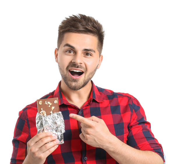 Komea nuori mies, jolla on maukas suklaa valkoisella taustalla - Valokuva, kuva
