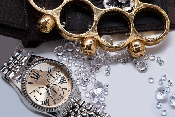 Латунні шнурки і золотий годинник між кришталевими діамантами на чоловічому гаманці, крупним планом з вибірковим фокусом. розкіш
 - Фото, зображення