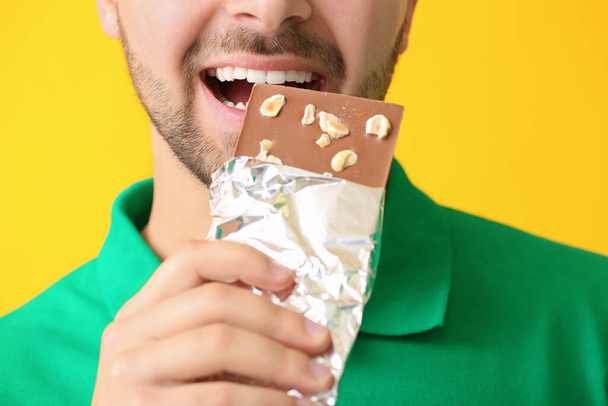 Komea nuori mies, jolla on maukas suklaa väritaustalla, lähikuva
 - Valokuva, kuva