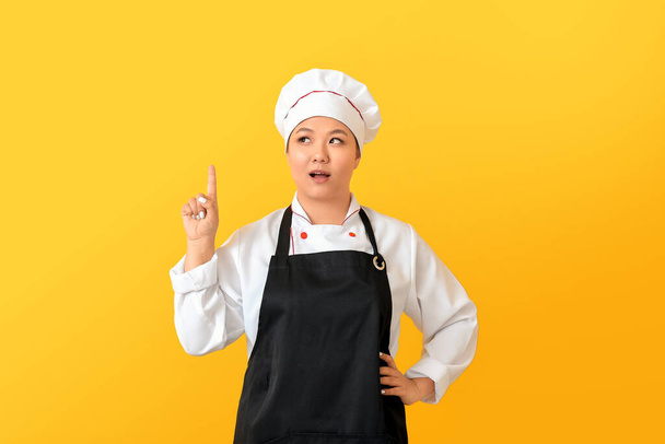 Hermoso chef asiático con el dedo índice levantado en el fondo de color
 - Foto, imagen