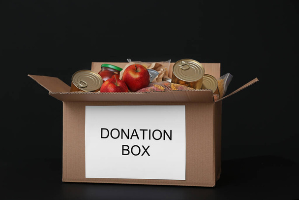 Κουτί δωρεάς με προϊόντα σε σκούρο φόντο - Φωτογραφία, εικόνα