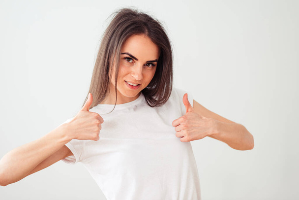 European woman shows thumb up with both hands and smiles sweetly. Happy girl on a light background - Photo, Image