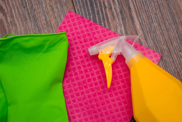 Close-up of a spray bottle, rubber gloves and a wet rag lying on the floor. The concept of disinfection of premises, the prevention of viral and bacterial diseases. Cleaning wooden surfaces. - 写真・画像