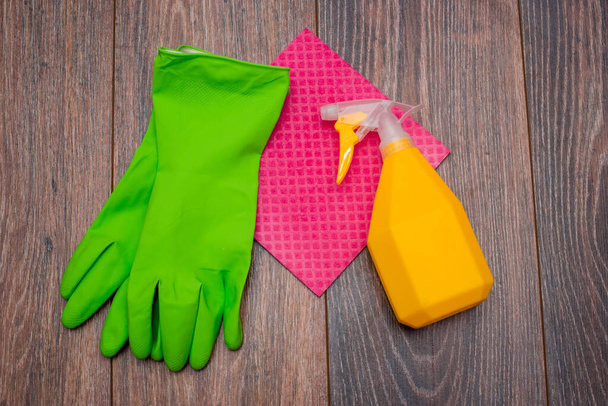 Close-up of a spray bottle, rubber gloves and a wet rag lying on the floor. The concept of disinfection of premises, the prevention of viral and bacterial diseases. Cleaning wooden surfaces. - Fotografie, Obrázek