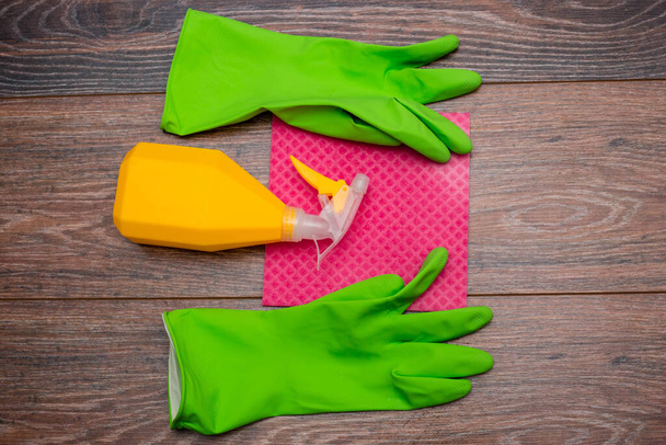 Close-up of a spray bottle, rubber gloves and a wet rag lying on the floor. The concept of disinfection of premises, the prevention of viral and bacterial diseases. Cleaning wooden surfaces. - Foto, immagini
