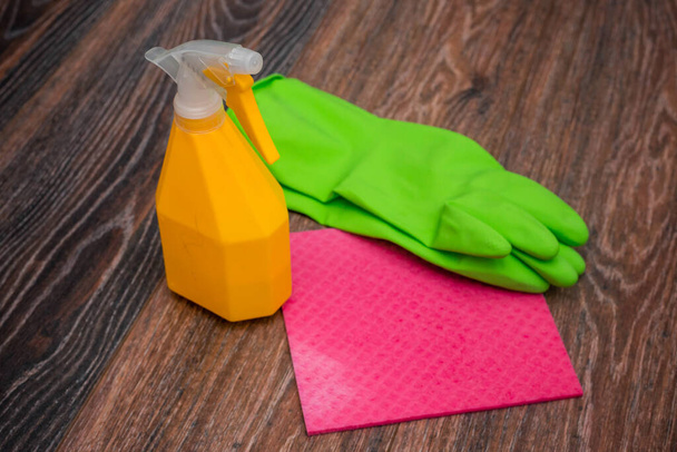 Close-up of a spray bottle, rubber gloves and a wet rag lying on the floor. The concept of disinfection of premises, the prevention of viral and bacterial diseases. Cleaning wooden surfaces. - Zdjęcie, obraz