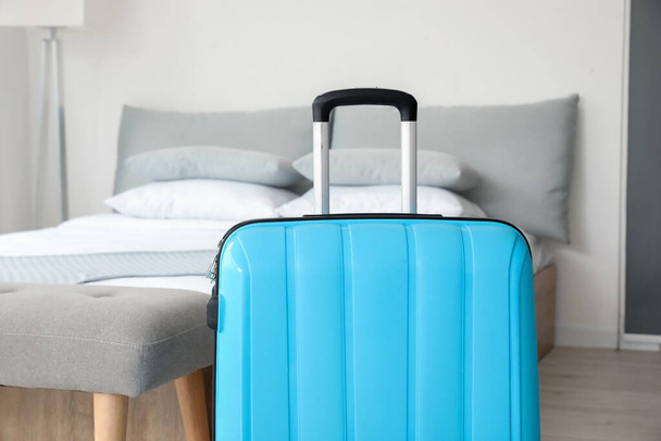 Βαλίτσα κοντά στο κρεβάτι στο δωμάτιο του ξενοδοχείου - Φωτογραφία, εικόνα