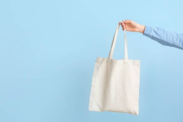 Female hand with eco bag on color background - Foto, afbeelding