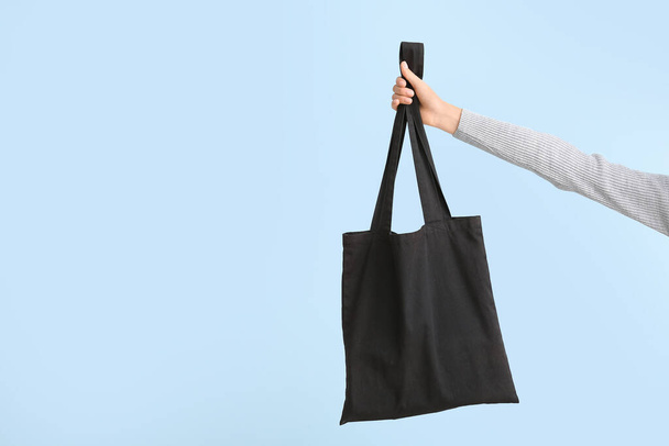 Mano femenina con bolsa ecológica sobre fondo de color
 - Foto, Imagen
