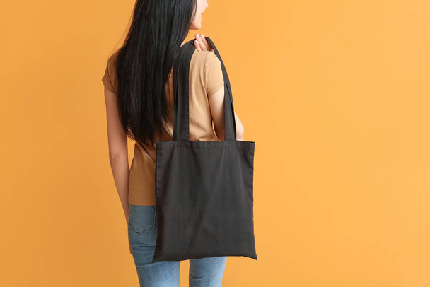 Young woman with eco bag on color background, back view - Foto, Bild