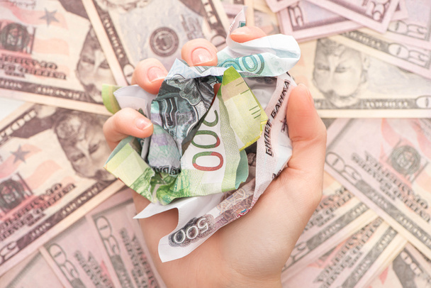 abgeschnittene Ansicht einer Frau, die zerknitterte Rubel-Banknoten in der Nähe von Dollars hält  - Foto, Bild