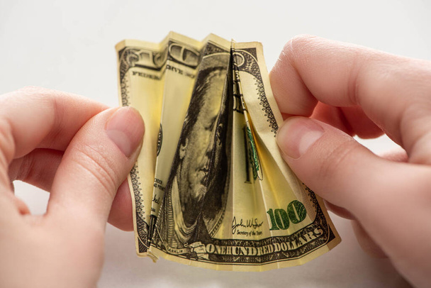 close up of woman holding crumpled dollar banknote in hands isolated on white  - 写真・画像