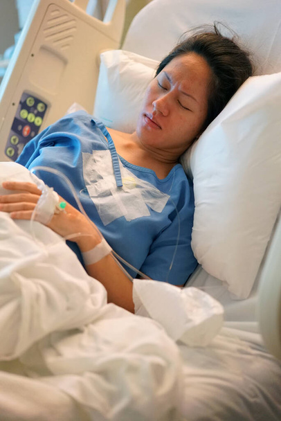 aziatische chinees vrouw patiënt liggend in het ziekenhuis bed fronsen en in pijn - Foto, afbeelding
