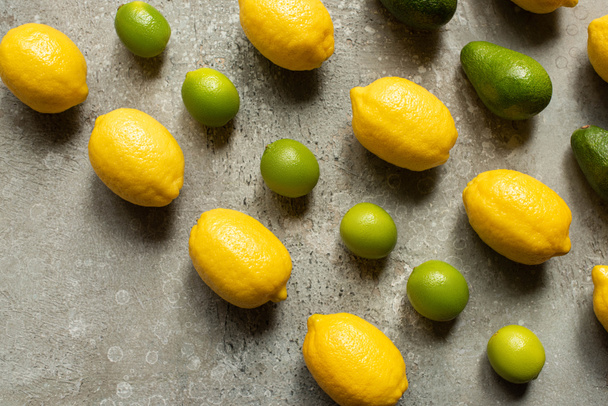 flat lay with colorful limes, avocado and lemons on grey concrete surface - Фото, изображение