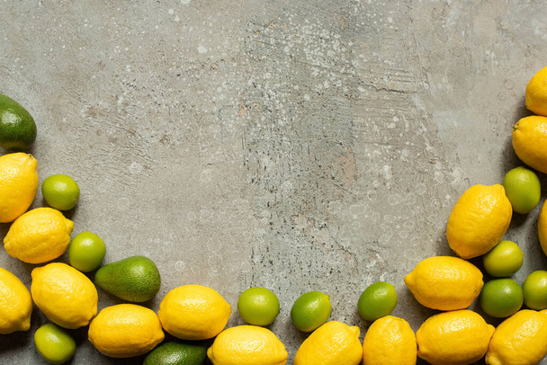 top view of colorful avocado, limes and lemons on grey concrete surface - Foto, Imagem
