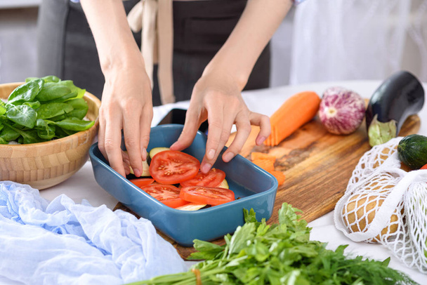 proceso de cocción de verduras con las manos, tomates colocados en bandeja para hornear, cena vegetariana, comidas caseras
 - Foto, imagen