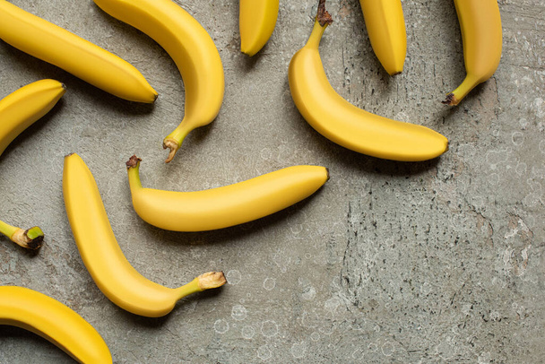 top view of colorful delicious bananas on grey concrete surface - Foto, Bild