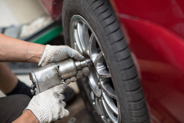 Reparación o cambio de neumáticos vehículo mecánico atornillar rueda del coche en la estación de servicio de reparación
 - Foto, imagen