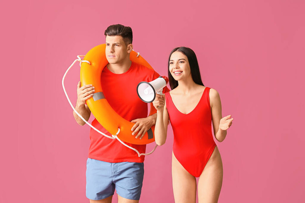 Beach rescuers with lifebuoy and megaphone on color background - 写真・画像