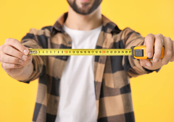 Young man with measuring tape on color background, closeup - Foto, afbeelding