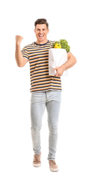 Happy man holding bag with food on white background - Photo, Image