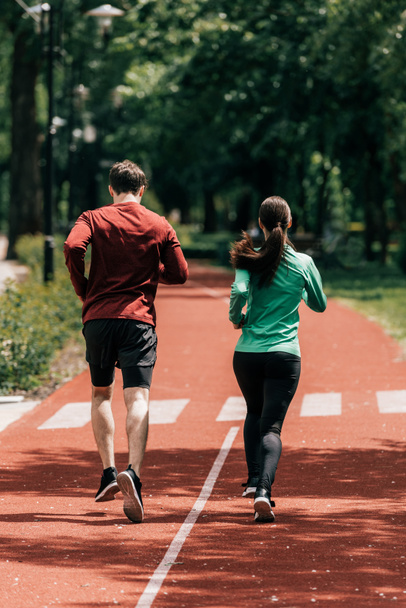 Back view of couple running on running path in park  - Valokuva, kuva