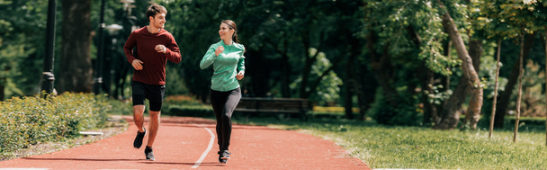 Panoramic crop of couple smiling at each other while jogging in park  - Photo, Image