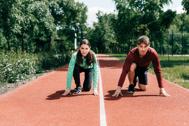 Pár stojí na startovní pozici na běžecké dráze v parku  - Fotografie, Obrázek