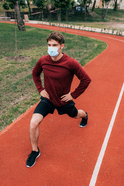 Людина в медичній масці робить легені, працюючи на біговій доріжці в парку
   - Фото, зображення