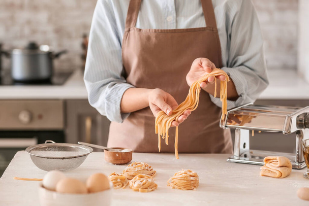 Woman preparing pasta in kitchen, closeup - Foto, Imagen
