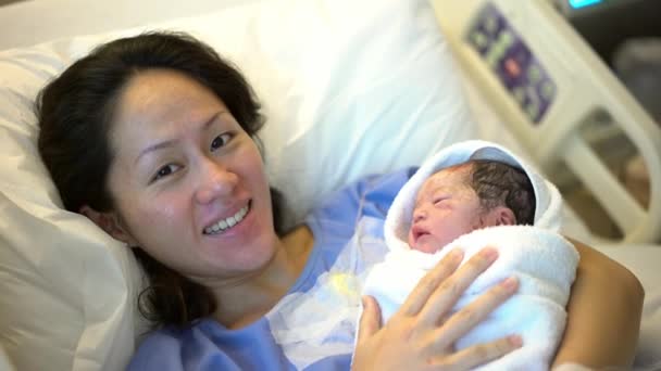 Азійська китайська мати лежить у лікарняному ліжку і виносить новонародженого. - Кадри, відео