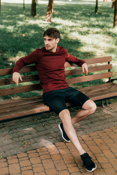 Handsome sportsman resting on bench in park  - Zdjęcie, obraz